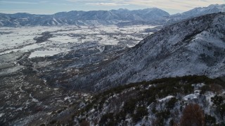 AX126_195 - 5.5K aerial stock footage fly over snowy Wasatch Range slopes to approach Heber Valley, Utah