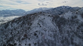AX126_196E - 5.5K aerial stock footage approach and fly over snowy Wasatch Range mountain in winter to reveal Midway, Utah