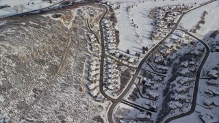 AX126_204E - 5.5K aerial stock footage orbit tract homes with snow in the shadow of a peak in Midway, Utah