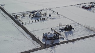 AX126_214 - 5.5K aerial stock footage orbit three large homes by snowy fields in wintertime, Midway, Utah