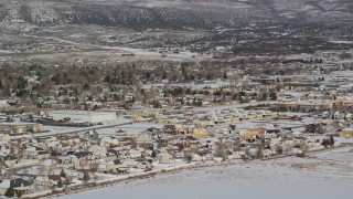 AX126_216 - 5.5K aerial stock footage orbit tract homes by snowy field on outskirts of Heber City in winter, Utah