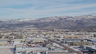 AX126_217 - 5.5K aerial stock footage of mountains with light snow seen from warehouse buildings in winter, Heber City, Utah