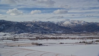 AX126_218E - 5.5K aerial stock footage of small town at the base of snowy mountain range in winter, Heber City, Utah
