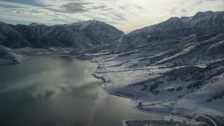 AX126_227 - 5.5K aerial stock footage approach snowy shore and mountains by the Deer Creek Reservoir in winter, Utah