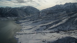 AX126_228 - 5.5K aerial stock footage approach snow mountains from frozen shore of Deer Creek Reservoir in winter, Utah