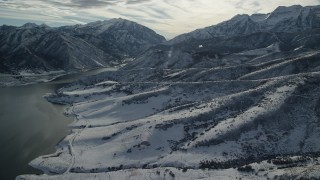 AX126_229 - 5.5K aerial stock footage approach snowy foothills of tall mountains on reservoir shore, Wasatch Range, Utah