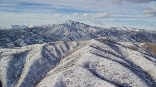 AX126_232E - 5.5K aerial stock footage a snowy Wasatch Range mountain with taller peak in the distance, Utah