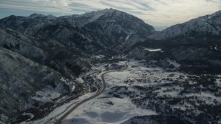 AX126_235 - 5.5K aerial stock footage approach road at the base of snowy mountains in winter, Wasatch Range, Utah