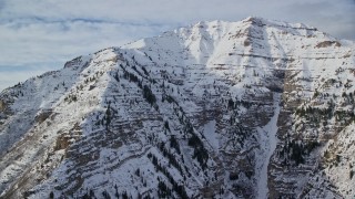 AX126_250E - 5.5K aerial stock footage of snowy, rugged slopes of Mount Timpanogos in winter, Utah