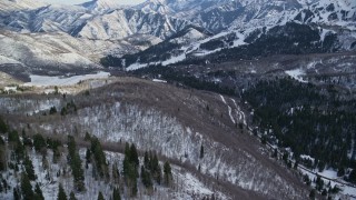 AX126_293E - 5.5K stock footage video fly over evergreens to approach Sundance Mountain Resort in winter, Utah