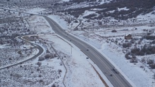 AX126_309 - 5.5K aerial stock footage orbit a country road through winter Snow with light traffic, Wasatch Range, Utah