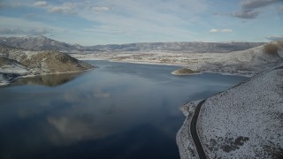 AX126_313 - 5.5K aerial stock footage of passing a highway on the shore of the reservoir and approach Heber City in winter, Utah
