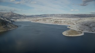 AX126_315 - 5.5K aerial stock footage approach Heber City from icy patches in the Deer Creek Reservoir in winter, Utah