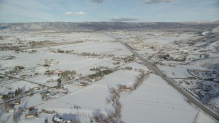 AX126_319 - 5.5K aerial stock footage of rural Heber City homes with winter snow near the highway in winter, Utah