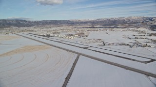 AX126_323 - 5.5K aerial stock footage orbit the runway at Heber City Municipal Airport with winter snow, Utah