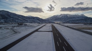 AX127_001E - 5.5K aerial stock footage of lifting off from Heber City Municipal Airport with winter snow, Utah