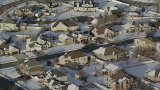 AX127_004 - 5.5K aerial stock footage tilt to tract homes in a small town neighborhood with winter snow, Heber City, Utah