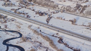 AX127_009E - 5.5K aerial stock footage of light traffic on highway through snowy countryside in winter, Heber City, Utah