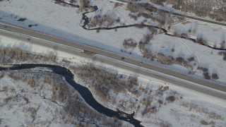 AX127_011 - 5.5K aerial stock footage of tacking two cars on a highway through snowy fields in wintertime, Heber City, Utah