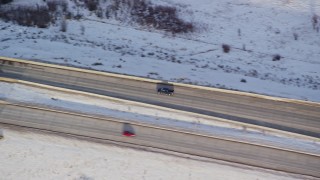 AX127_012 - 5.5K aerial stock footage of tracking a black truck on a county highway and crossing a small bridge in winter, Heber City, Utah