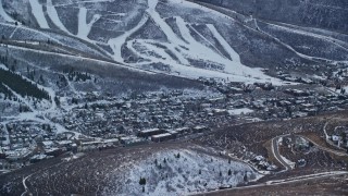 AX127_020E - 5.5K aerial stock footage of the small town of Park City in the shadow of snowy mountain in winter at sunset, Utah