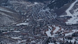 AX127_029E - 5.5K aerial stock footage of Park City at sunset in the shadow of a snowy mountain in winter, Utah