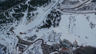 AX127_038 - 5.5K aerial stock footage reverse view of the aerials pool and ski jumps at Utah Olympic Park with winter snow at sunset, Utah