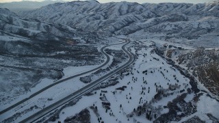 AX127_053 - 5.5K aerial stock footage approach I-80 with light traffic through a wintery Wasatch Range pass at sunset, Utah