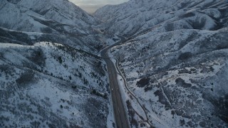 AX127_058 - 5.5K aerial stock footage of I-80 through narrow mountain pass at sunset in winter, Wasatch Range, Utah