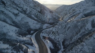 AX127_063 - 5.5K aerial stock footage of interstate through Wasatch Range with winter snow at sunset, Utah