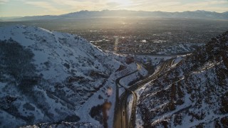 AX127_070E - 5.5K aerial stock footage approach Salt Lake City suburbs from I-80 through Wasatch Range at sunset, Utah