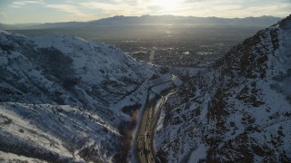 AX127_071 - 5.5K aerial stock footage of I-80 through wintery Wasatch Range mountain pass toward Salt Lake City at sunset, Utah