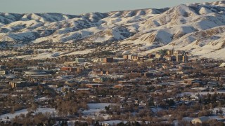 AX127_077 - 5.5K aerial stock footage of approaching the University of Utah campus at the base of snowy mountains at sunset