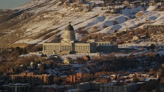AX127_104E - 5.5K aerial stock footage orbit Utah State Capitol by snowy hills at sunset in wintertime, Salt Lake City