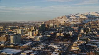 AX127_107E - 5.5K aerial stock footage orbit Downtown Salt Lake City near Utah State Capitol at sunset with winter snow