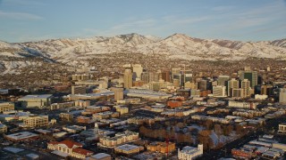 AX127_113E - 5.5K aerial stock footage of wide orbit of Downtown Salt Lake City with winter snow at sunset, Utah