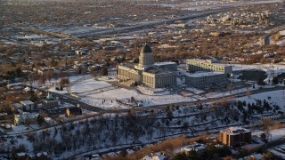 AX127_125 - 5.5K aerial stock footage reverse view of the Utah State Capitol at sunset with winter snow, Salt Lake City