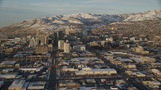 AX127_134 - 5.5K stock footage aerial video approach Downtown Salt Lake City between Main and State Streets at sunset with winter snow, Utah