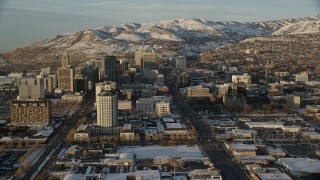 AX127_135 - 5.5K stock footage aerial video approach State Street through Downtown Salt Lake City at sunset with winter snow, Utah
