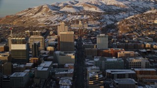 AX127_136E - 5.5K aerial stock footage of following State Street through Downtown Salt Lake City toward the state capitol at sunset in winter, Utah