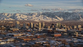 AX127_145E - 5.5K aerial stock footage a view of Downtown Salt Lake City and distant snow mountains at sunset in winter, Utah