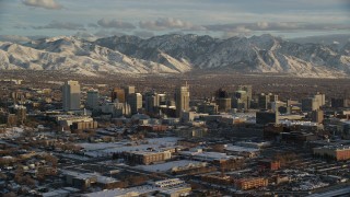 AX127_146 - 5.5K stock footage aerial video slow orbit of Downtown Salt Lake City with distant snow mountains at sunset, Utah