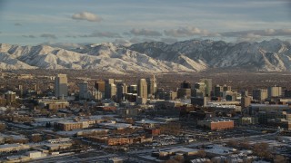 AX127_147 - 5.5K stock footage aerial video of orbiting Downtown Salt Lake City with distant snow mountains at sunset in wintertime, Utah