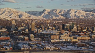 AX127_149E - 5.5K aerial stock footage of Downtown Salt Lake City at sunset with winter snow, Utah