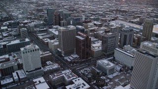 AX127_166 - 5.5K stock footage aerial video orbit office buildings in Downtown Salt Lake City at sunset with winter snow, Utah