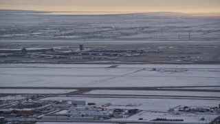 AX127_170E - 5.5K aerial stock footage of SLC Airport with winter snow as an airliner races by at sunset, Utah