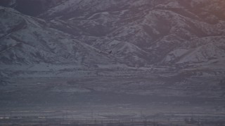 AX127_172 - 5.5K aerial stock footage of tracking a commercial airline gaining altitude at sunset in winter, Salt Lake City, Utah