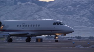AX128_001E - 5.5K aerial stock footage of tracking taxiing civilian jet at SLC Airport with winter snow at sunset, Utah