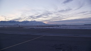 AX128_003 - 5.5K aerial stock footage of low altitude approach to taxiways and winter snow at SLC Airport at sunset, Utah