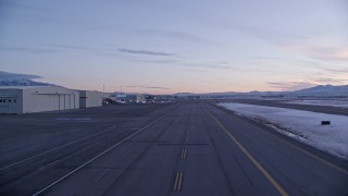 AX128_004 - 5.5K aerial stock footage of ascending near hangars and parked planes at SLC Airport in winter at sunset, Utah